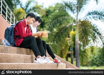 Male and female students sitting and reading books on the stairs.