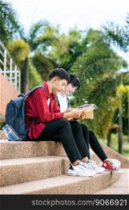 Male and female students sitting and reading books on the stairs.