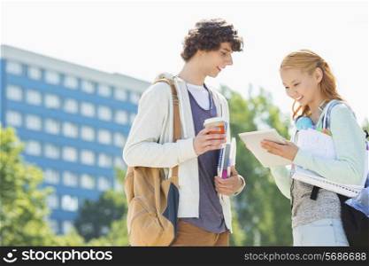 Male and female students using digital tablet at college campus