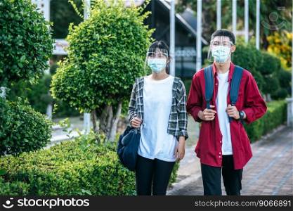 Male and female students wear face chill and masks Walk the footpath