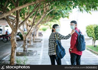 Male and female students wear face chill and masks Walk the footpath