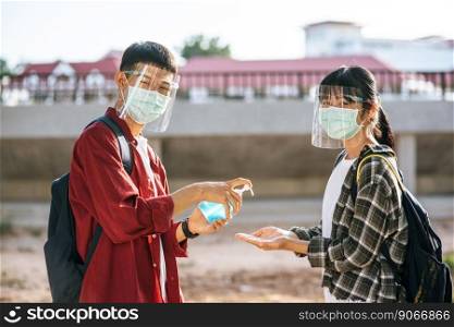 Male and female students wear masks and squeeze the gel to wash their hands.