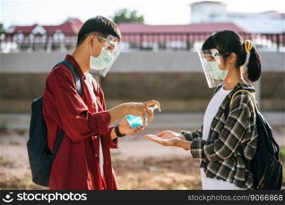 Male and female students wear masks and squeeze the gel to wash their hands.
