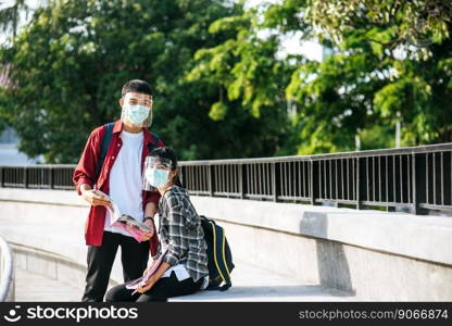 Male and female students wearing masks sit and read books on the stairs