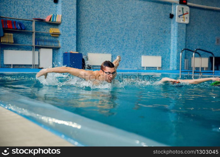 Male and female swimmers swims in the pool. Man and woman in the water, sport swimming skill training, motion view, workout before competition. Male and female swimmers swims in the pool