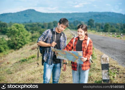 Male and female tourists standing look at the roadside map.