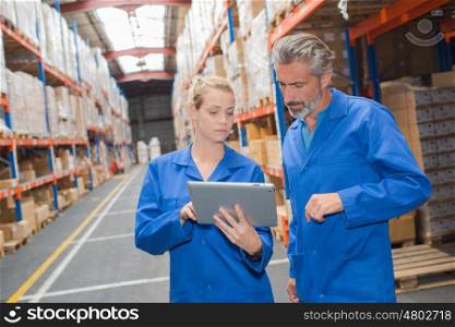 Male and female warehouse workers looking at tablet