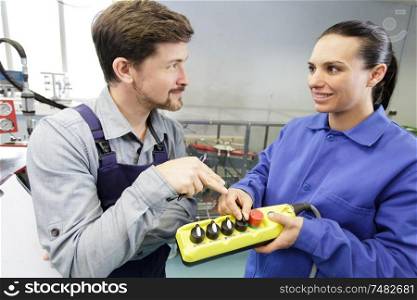 male and female workers looking at factory machinery