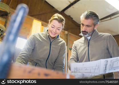 male and female workers looking at plans in workshop