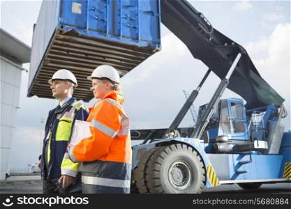 Male and female workers standing by freight vehicle in shipping yard