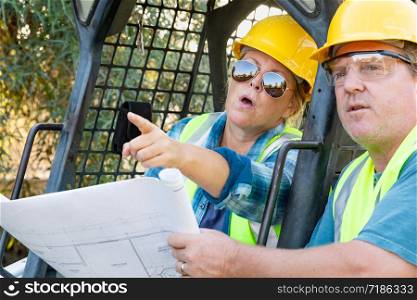 Male and Female Workers With Technical Blueprints Talking at Construction Site