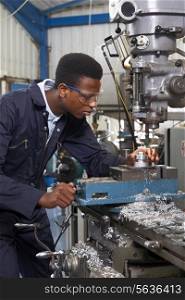 Male Apprentice Engineer Working On Drill In Factory