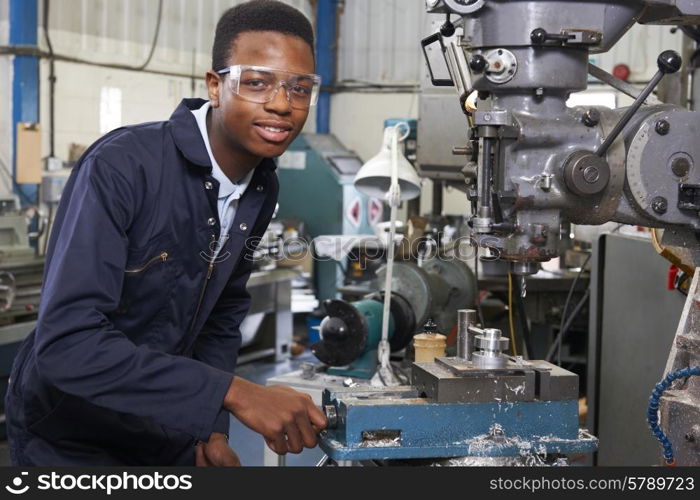 Male Apprentice Engineer Working On Drill In Factory