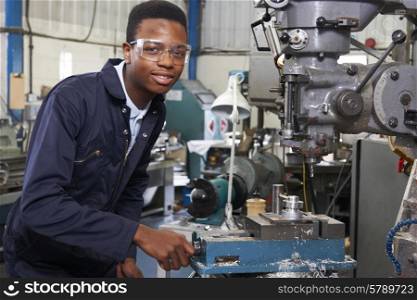 Male Apprentice Engineer Working On Drill In Factory