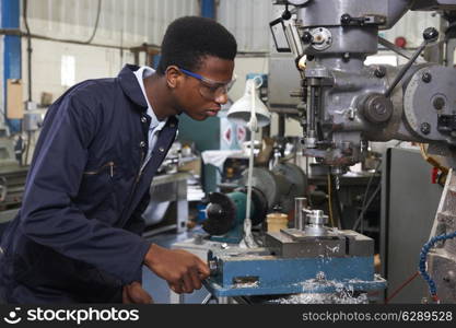 Male Apprentice Engineer Working On Drill In Factory