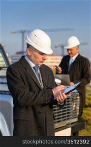 Male architect developers on construction site making notes building project