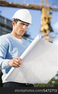 Male architect examining blueprint at construction site