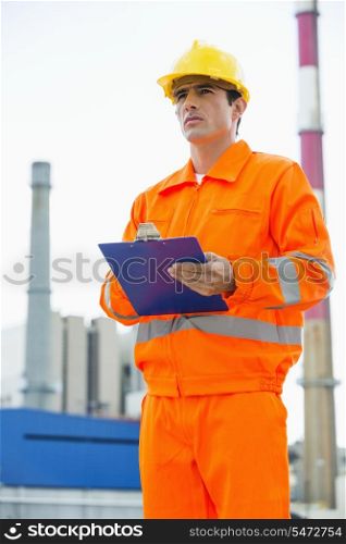 Male architect holding clipboard while standing at site