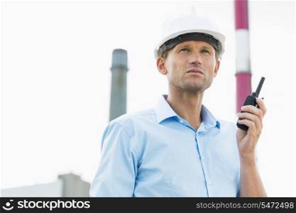 Male architect holding walkie-talkie at site