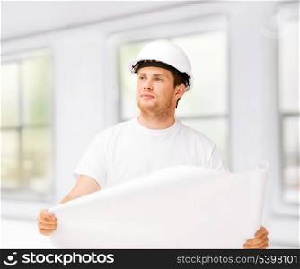 male architect in helmet looking at blueprint at home