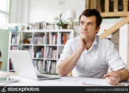 Male architect in office. Male architect with computer studying plans in office