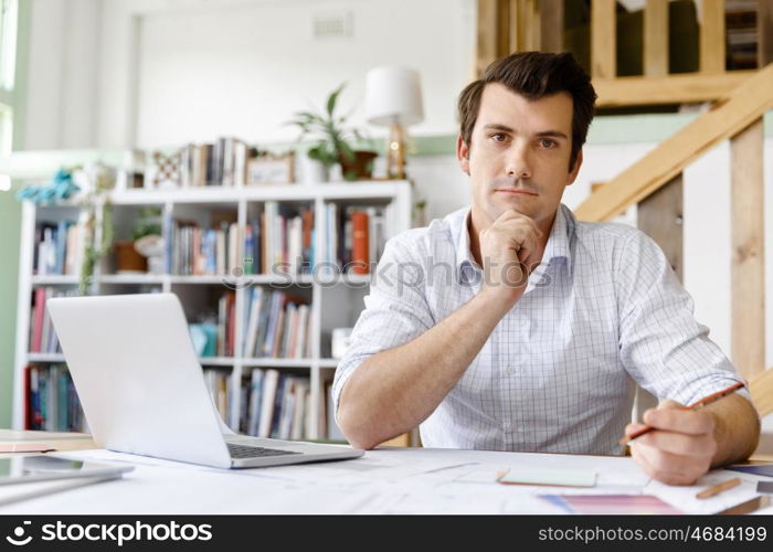 Male architect in office. Male architect with computer studying plans in office