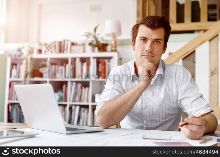 Male architect in office. Male architect with computer studying plans in office