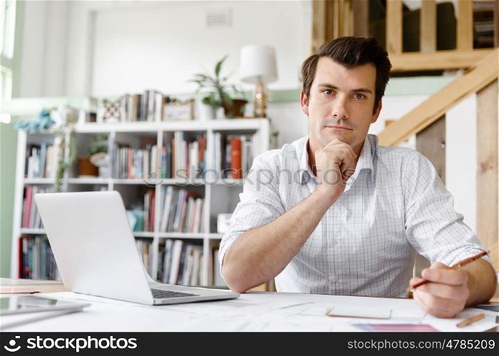 Male architect in office. Male architect with computer studying plans in office