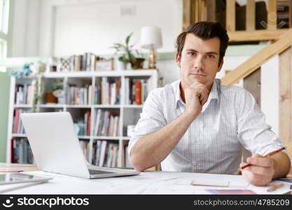 Male architect in office. Male architect with computer studying plans in office