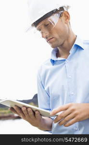 Male architect looking at tablet PC against sky