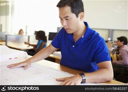 Male Architect Studying Plans In Office