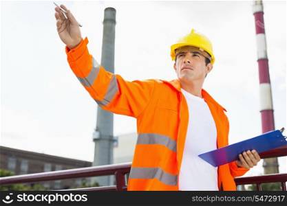 Male architect with clipboard at industry