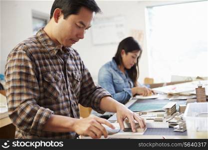 Male Architect Working On Model In Office