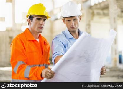 Male architects analyzing blueprint at construction site