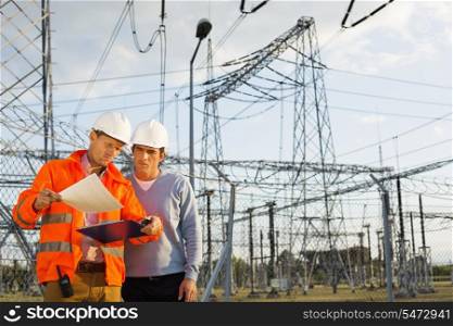 Male architects reviewing documents together at electric power plant