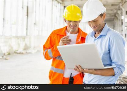 Male architects using laptop at construction site