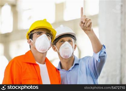 Male architects wearing protective mask while working at construction site