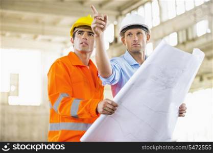 Male architects with blueprint working at construction site