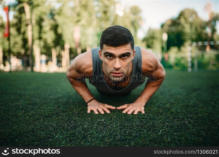 Male athlete doing push-up exercise on outdoor fitness workout. Sportsman on the training in park. Athlete doing push-up exercise on outdoor workout