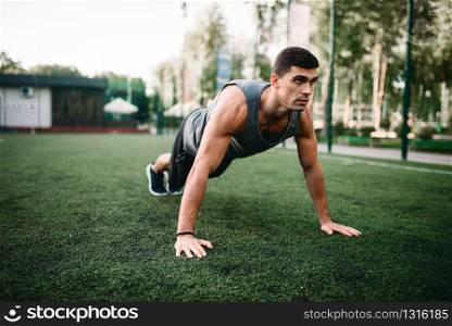 Male athlete doing push-up exercise on outdoor fitness workout. Sportsman on the training in park