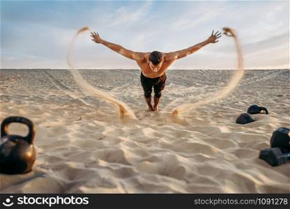Male athlete doing push-up exercises in desert at sunny day, flying sand effect. Strong motivation in sport, strength outdoor training