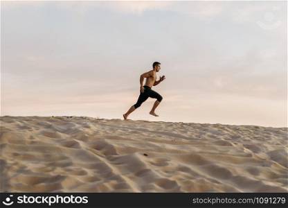 Male athlete on running workout in desert at sunny day. Strong motivation in sport, strength outdoor training