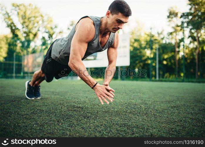 Male athlete on training, push-up exercise in action, fitness workout. Sportsman in park