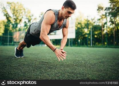 Male athlete on training, push-up exercise in action, fitness workout. Sportsman in park