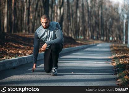 Male athlete prepares to run, training outdoor. Jogger on morning workout. Athletic man running in park