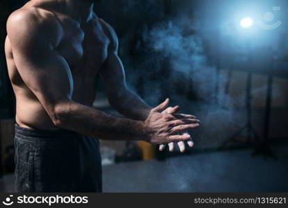 Male athlete rubs hands with talcum powder. Gymnast prepare for exercises, rubbing talc