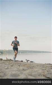 Male athlete/runner running on beach - jog workout well-being concept