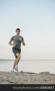 Male athlete/runner running on beach - jog workout well-being concept