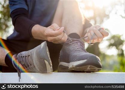 Male athlete tying shoe laces in minimalistic barefoot sneakers getting ready for training. Sport workout and healthy lifestyle concept.