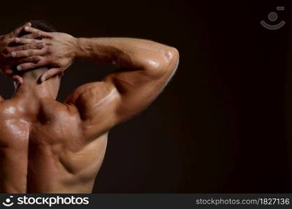 Male athlete with muscular body poses in studio, back view, dark background. One man with athletic build, shirtless sportsman in jeans pants, active healthy lifestyle. Male athlete with muscular body, back view